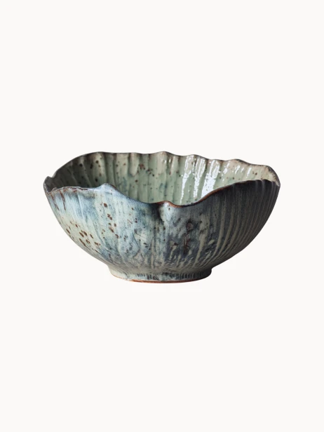 Rustykalna ceramiczna miska pokryta melanżowym jasnoniebieskim i beżowym szkliwem z brązowymi, nakrapianymi detalami na jednolitym białym tle.