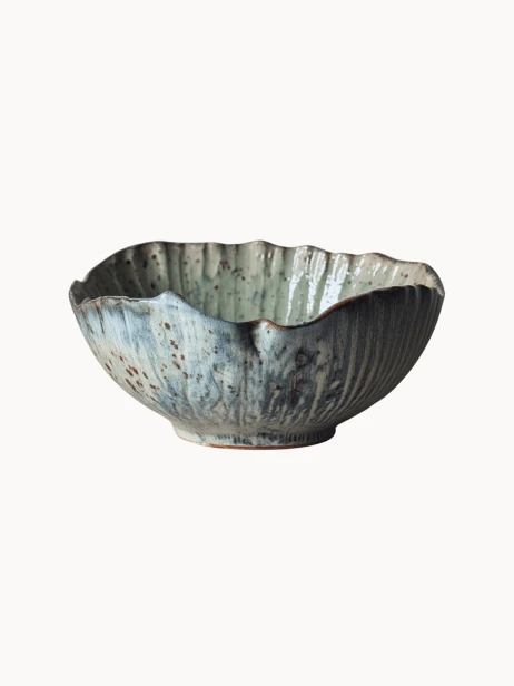 Rustykalna ceramiczna miska pokryta melanżowym jasnoniebieskim i beżowym szkliwem z brązowymi, nakrapianymi detalami na jednolitym białym tle.